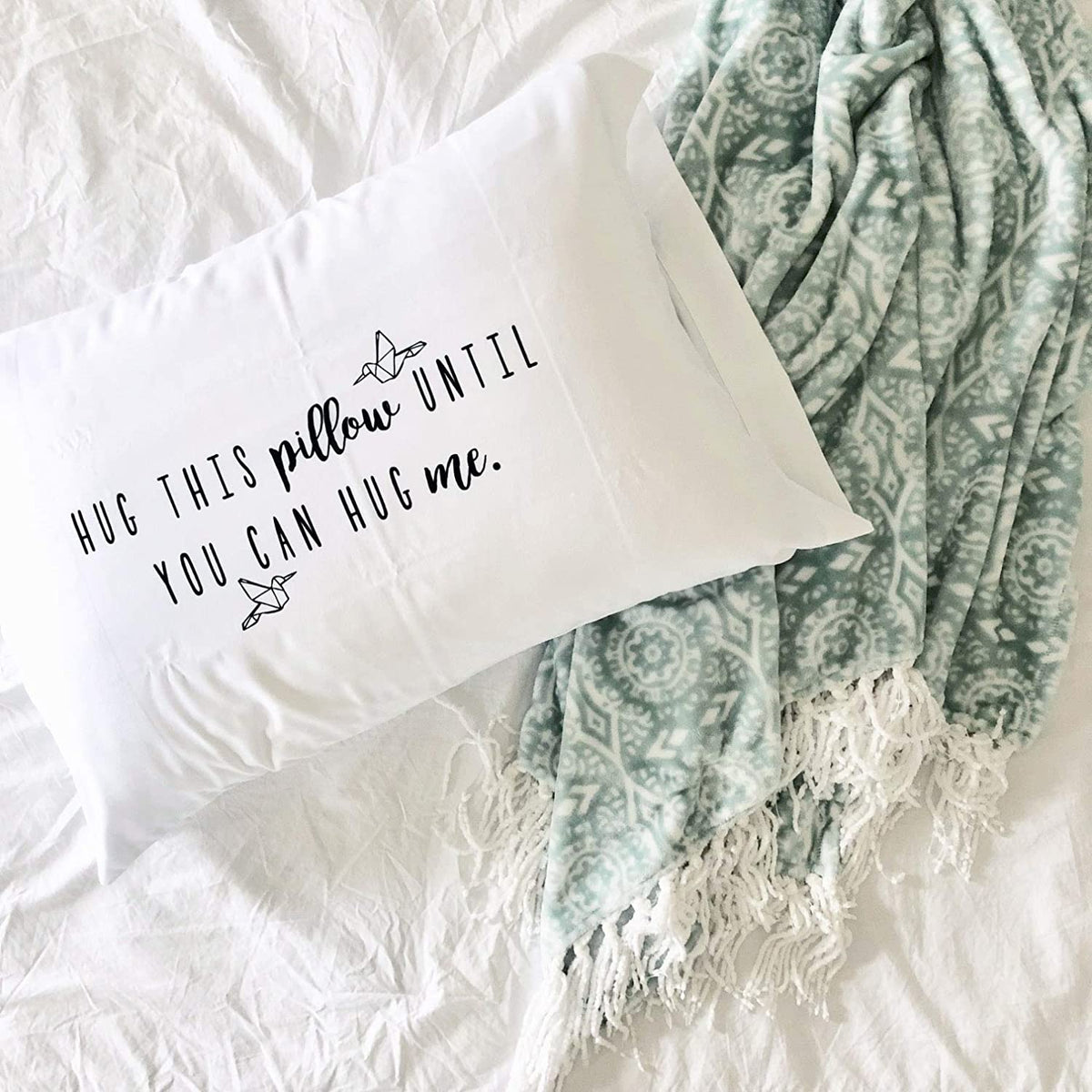 Hug This Pillow Until You Can Hug Me pillowcase on a bed with two paper cranes